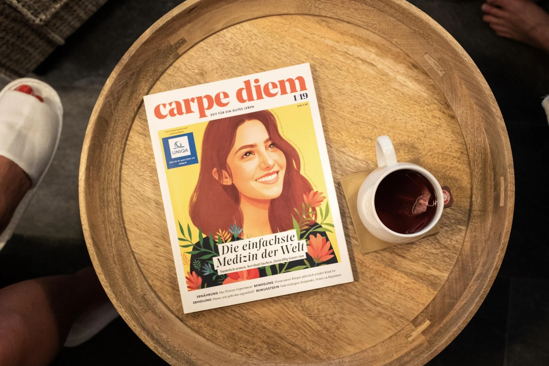 Auszeit für mich Zeitschrift Carpe Diem und Tasse mit Tee auf einem runden Holztisch