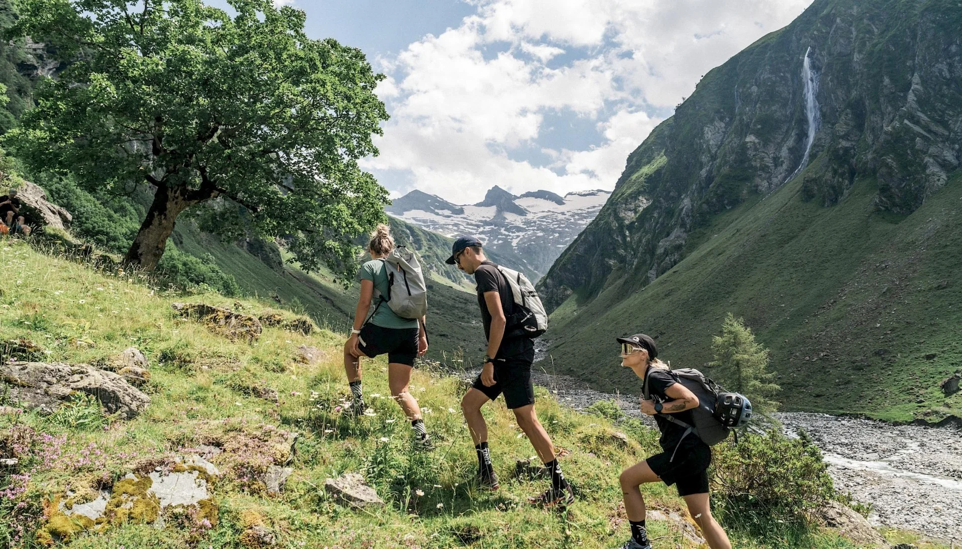 Three hikers trekking uphill in the mountains on a sunny day