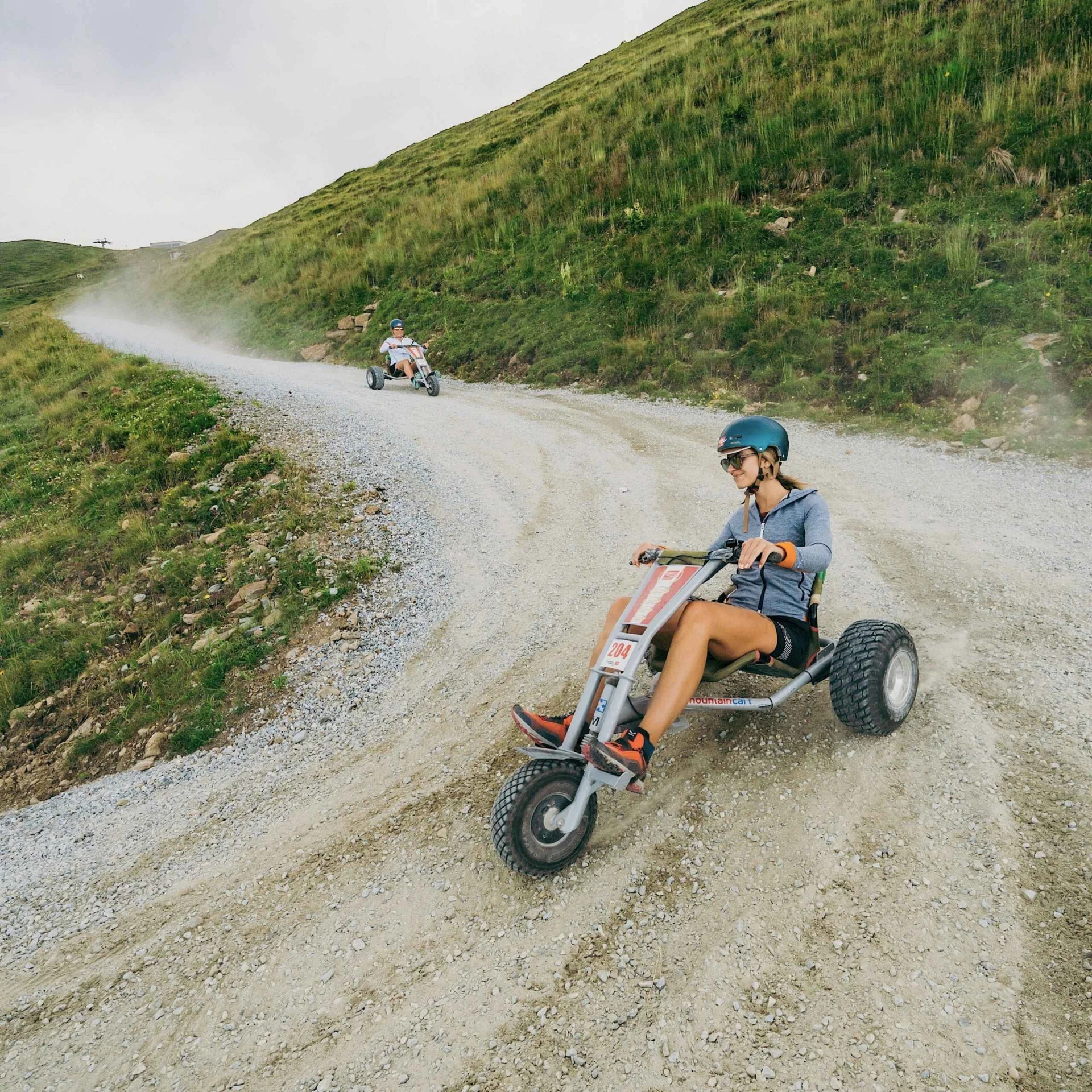 Spielend leichte Familienzeit im Hotel Gassner Zwei Kinder fahren auf einem Schotterweg in der Wildkogel-Arena mit den Mountaincarts bergab