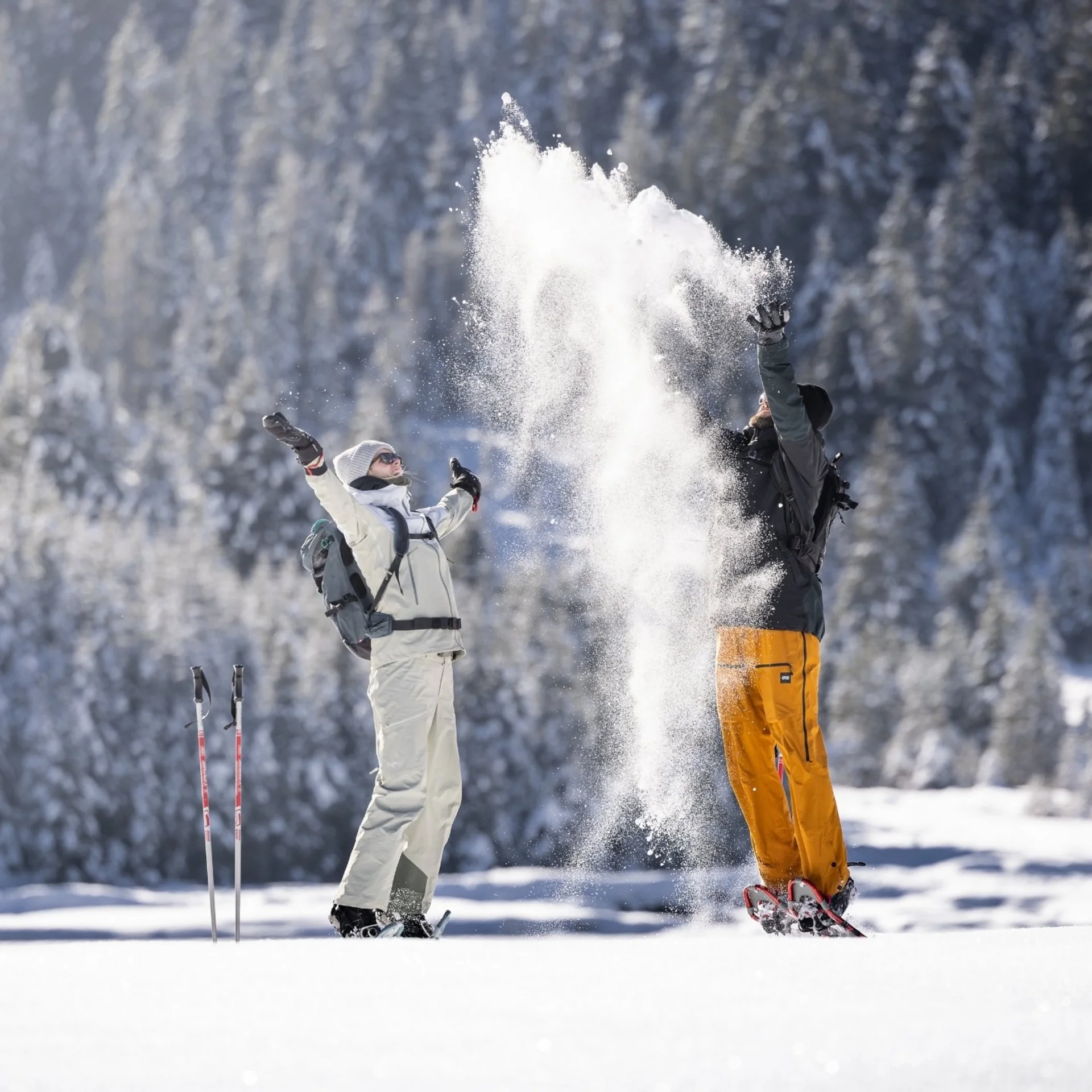 Winterkinder unter sich Zwei Menschen werfen Schnee in die Luft in einer verschneiten Winterlandschaft.