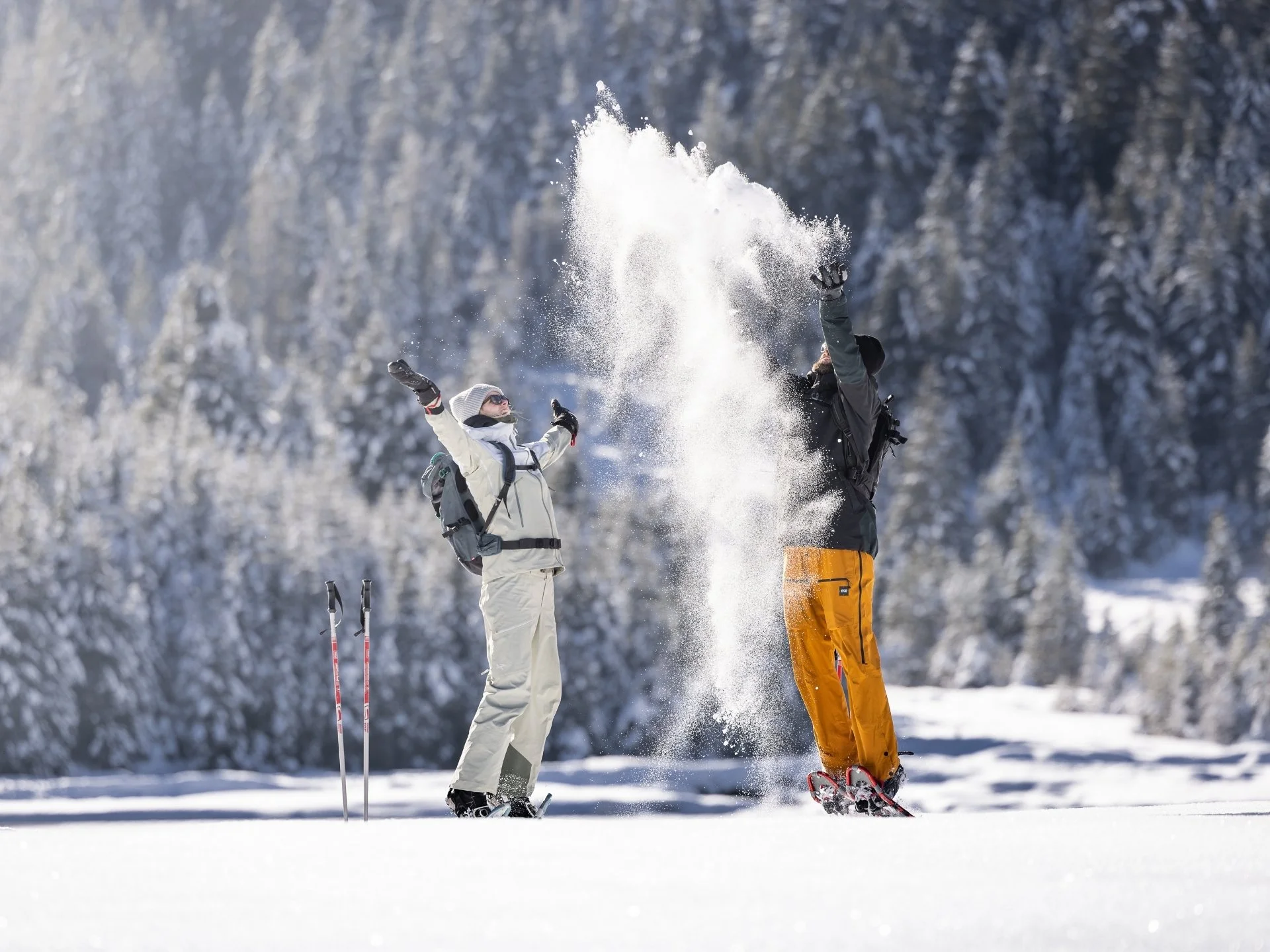 Winterkinder unter sich Zwei Menschen werfen Schnee in die Luft in einer verschneiten Winterlandschaft.