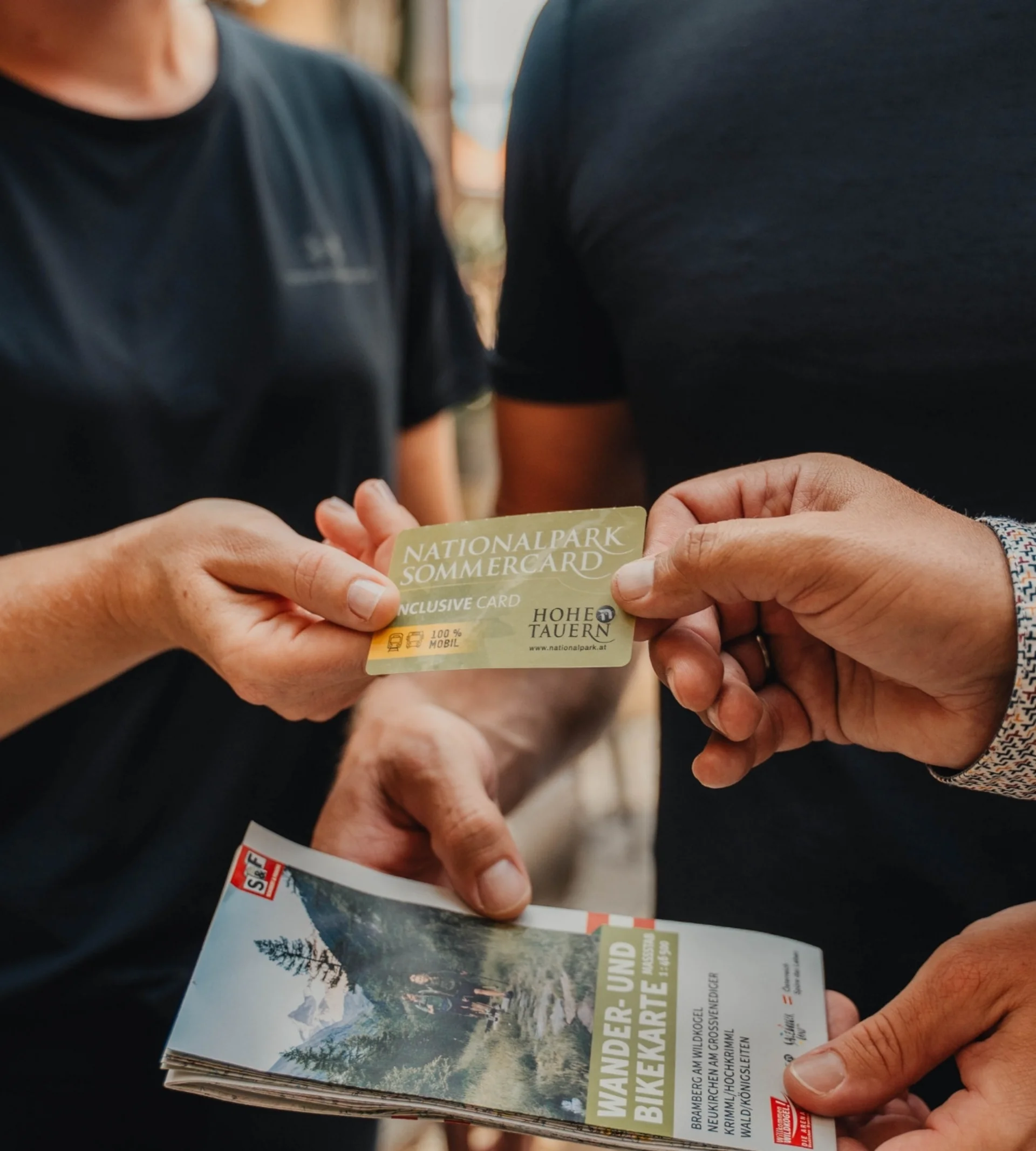 Home Person übergibt Nationalpark Sommercard an anderen, hält Wander- und Bikerkarte