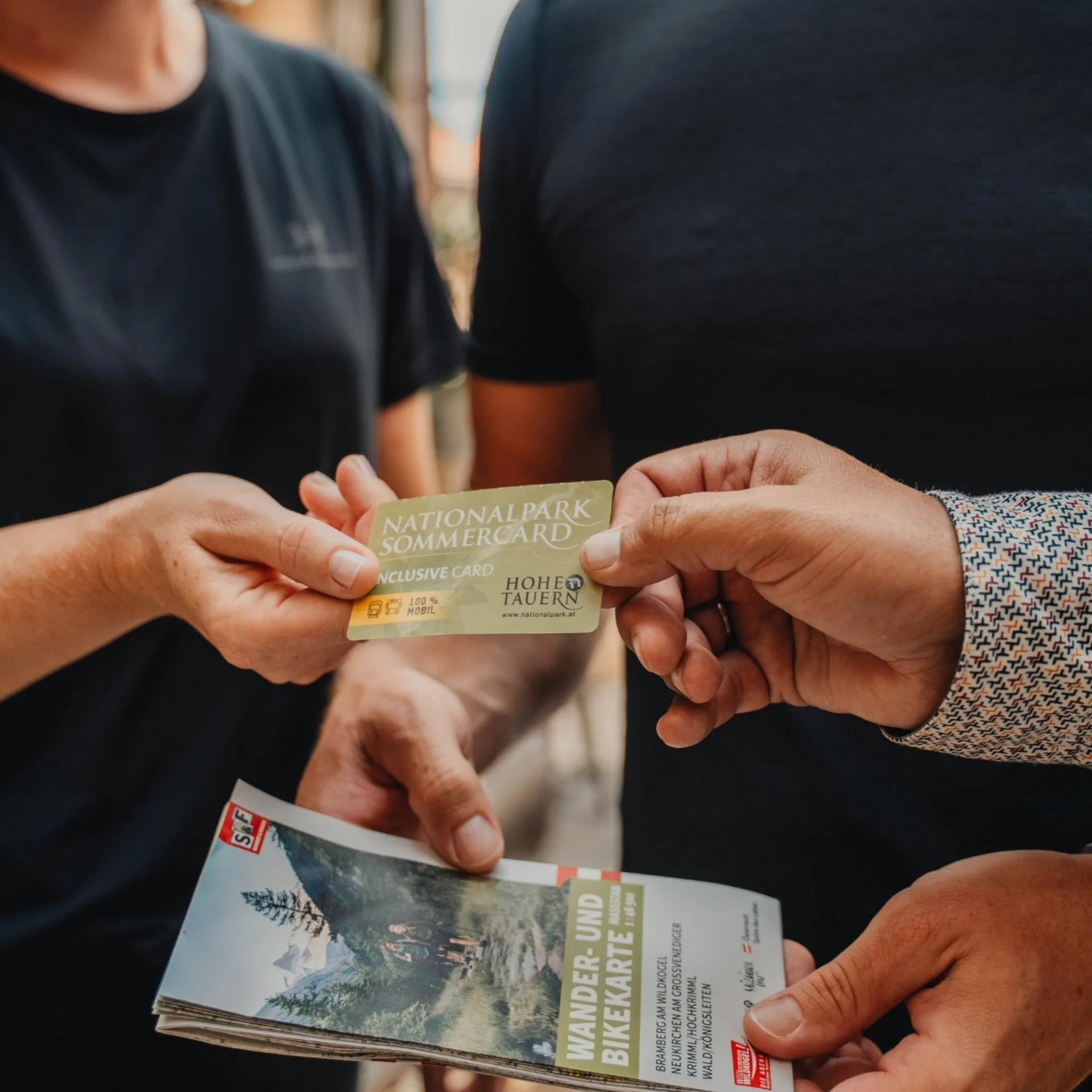 Person handing over National Park Summer Card holding hiking and biking map