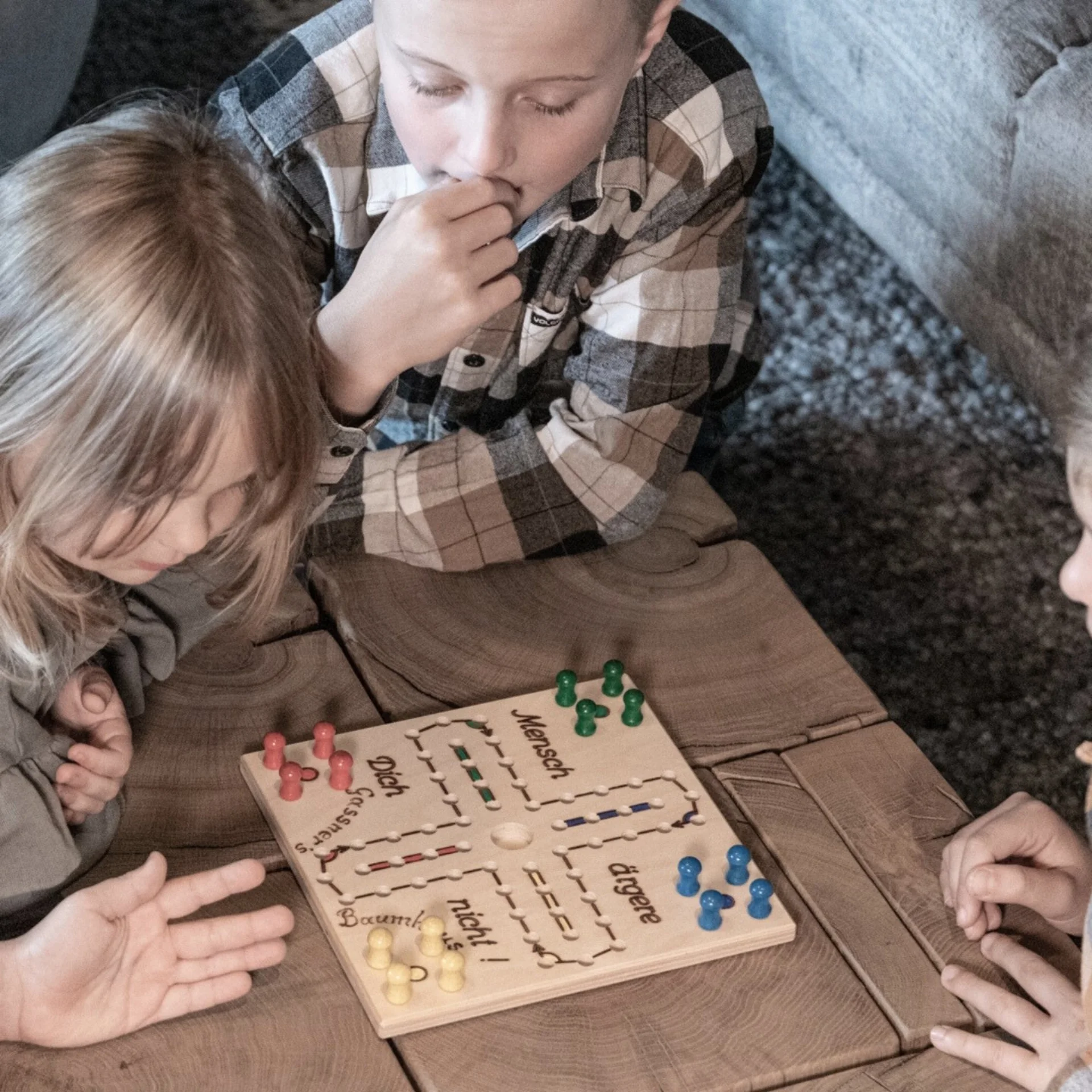 Four children playing Ludo on a wooden table