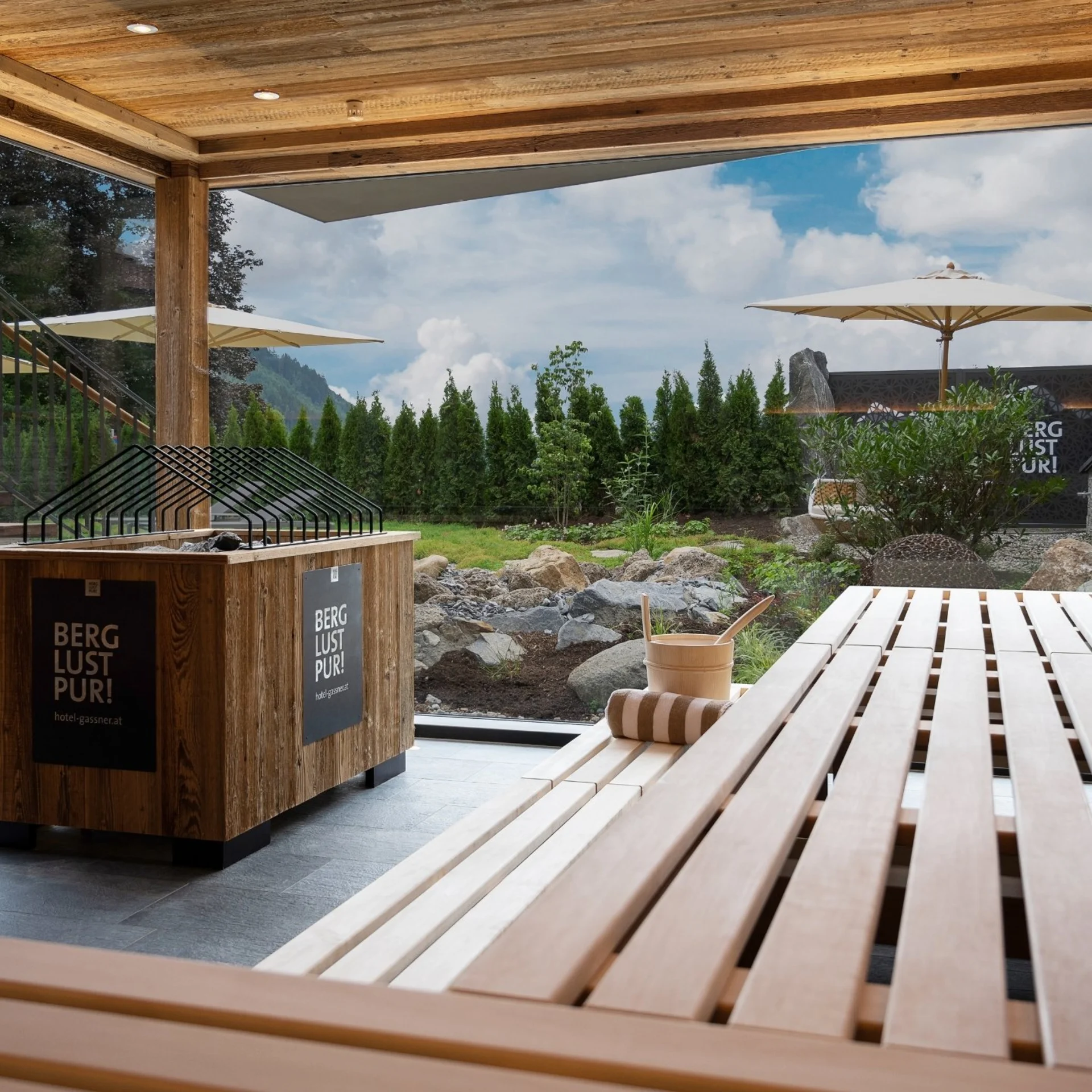 Moderner Holzsauna mit Blick auf Garten und Berge bei Tageslicht