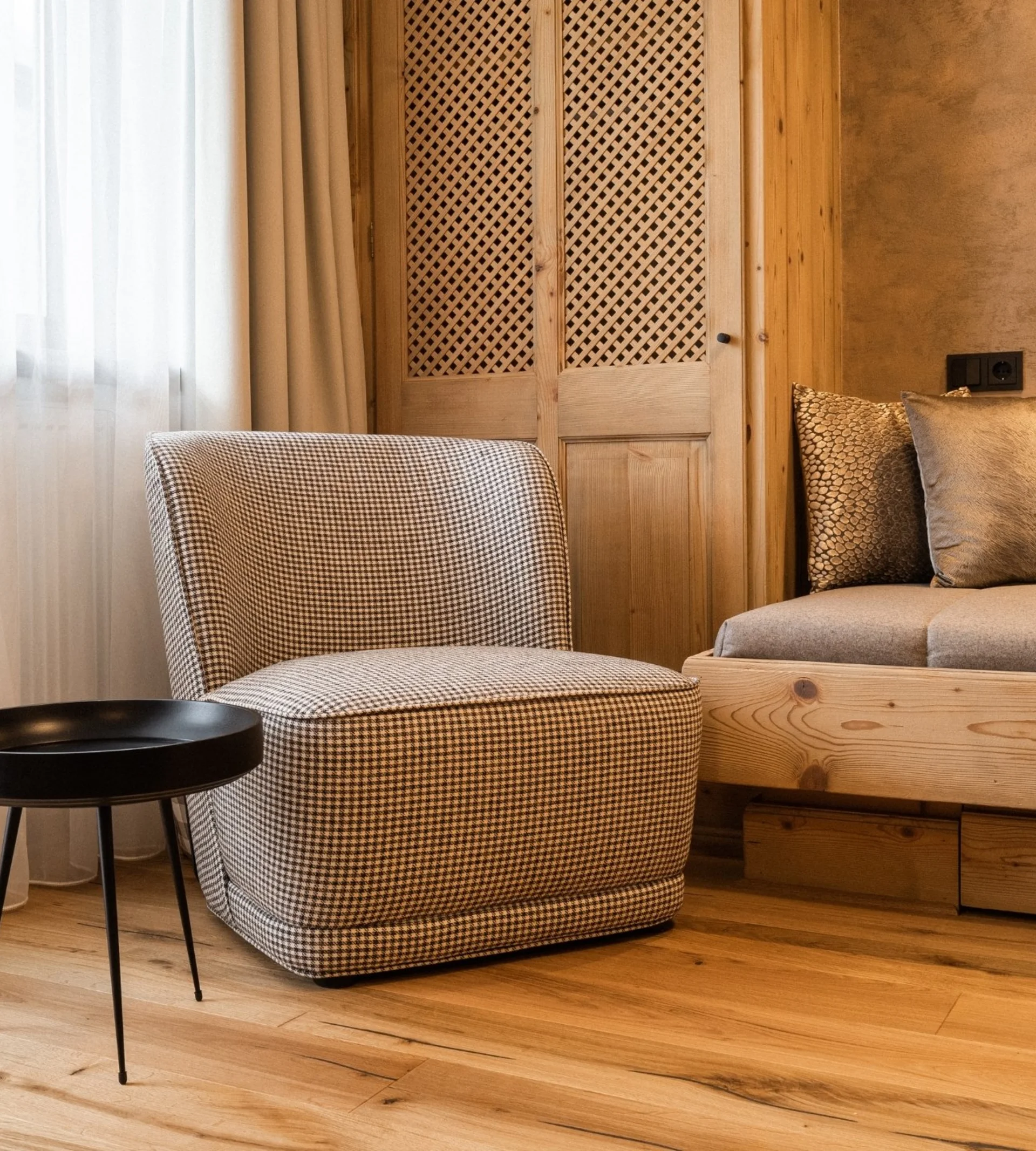 Model and slope flying Cozy seating area with checkered chair, small table, and wooden furniture in warm room