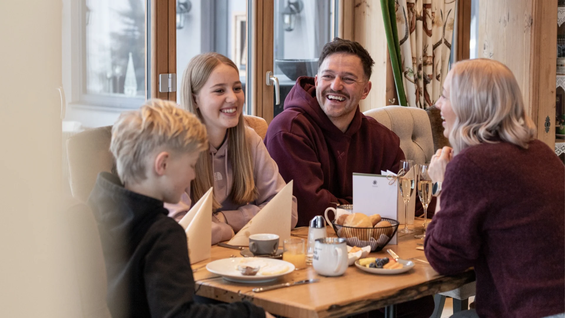 Spielend leichte Familienzeit im Hotel Gassner Familie genießt gemeinsame Zeit und Lachen beim Frühstück am Holztisch