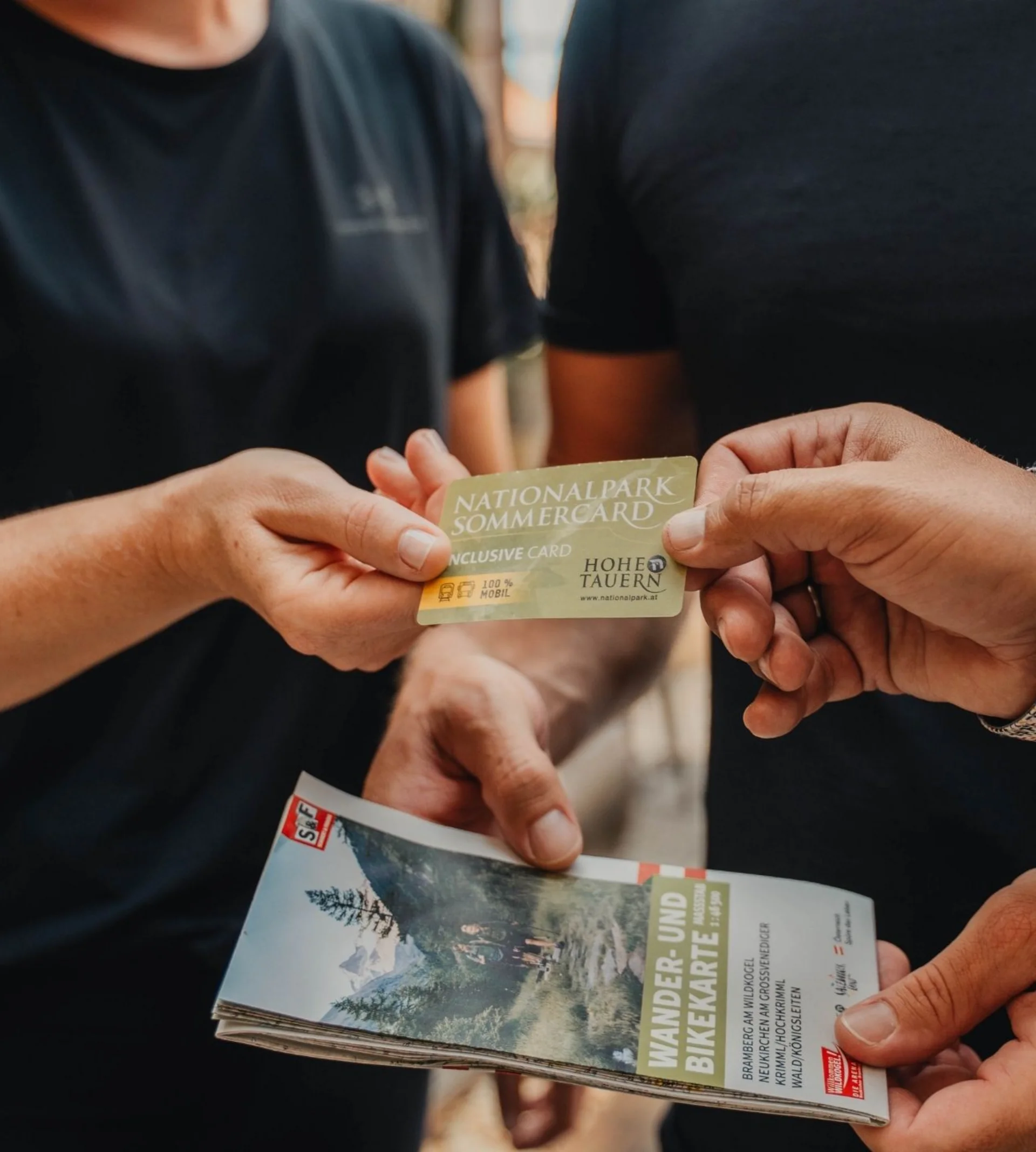 Personen tauschen Nationalpark Sommercard und Wander- und Bikekarte aus