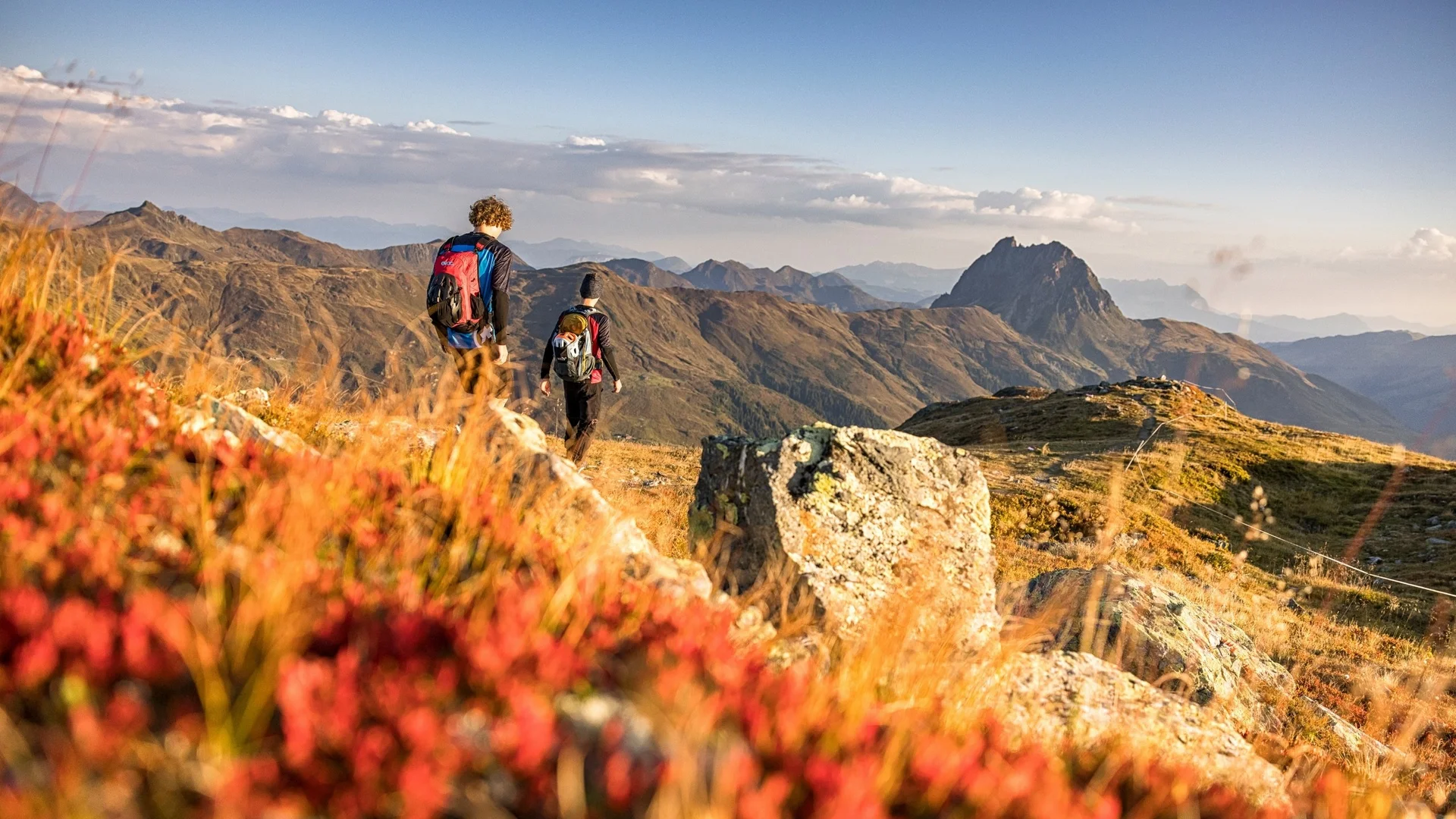 Salzburger Bauernherbst trifft auf Wild-Watching Zwei Wanderer auf einem Berggrat mit Blick auf eine weitläufige Berglandschaft