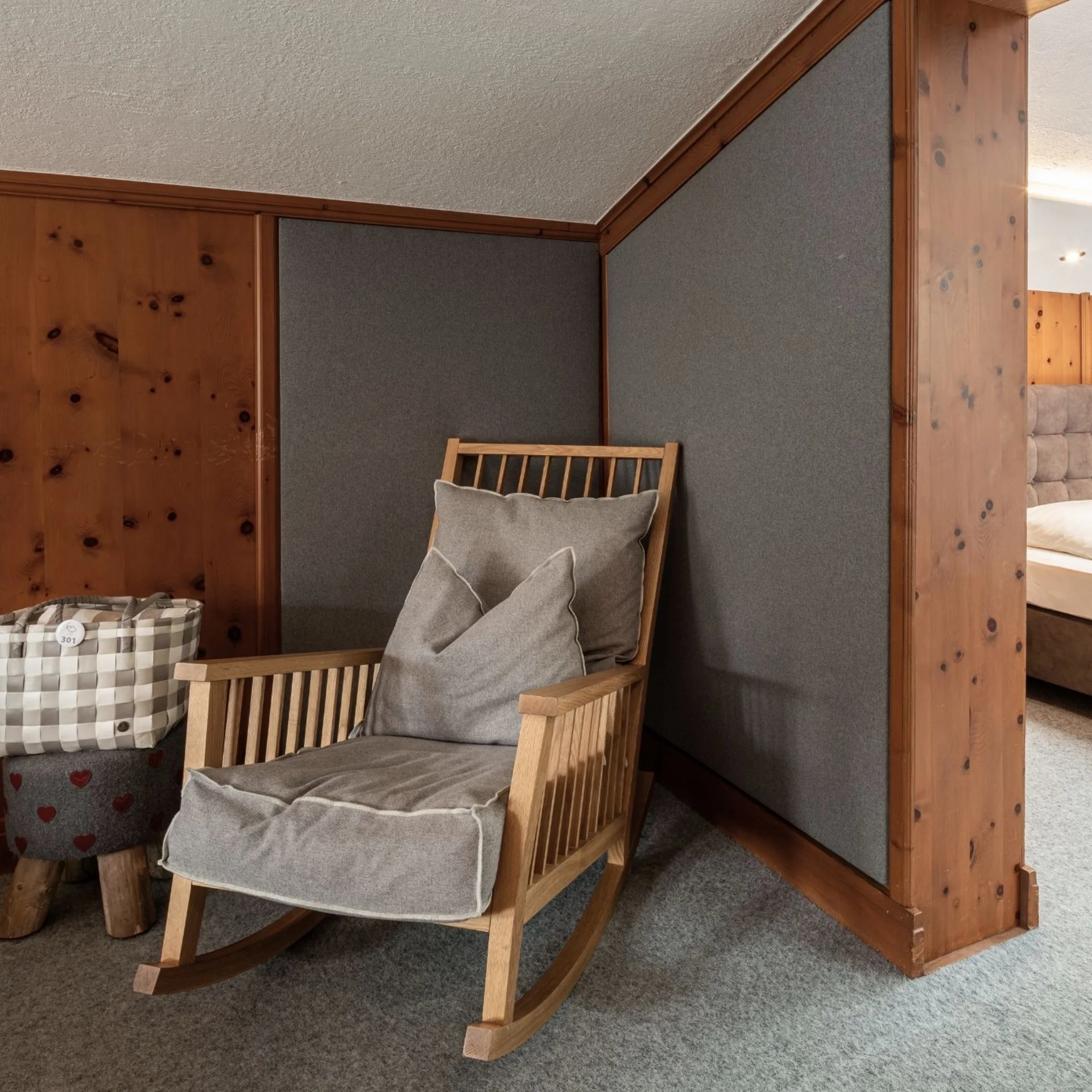 Cozy rocking chair with cushions next to bedroom with mirrored wall