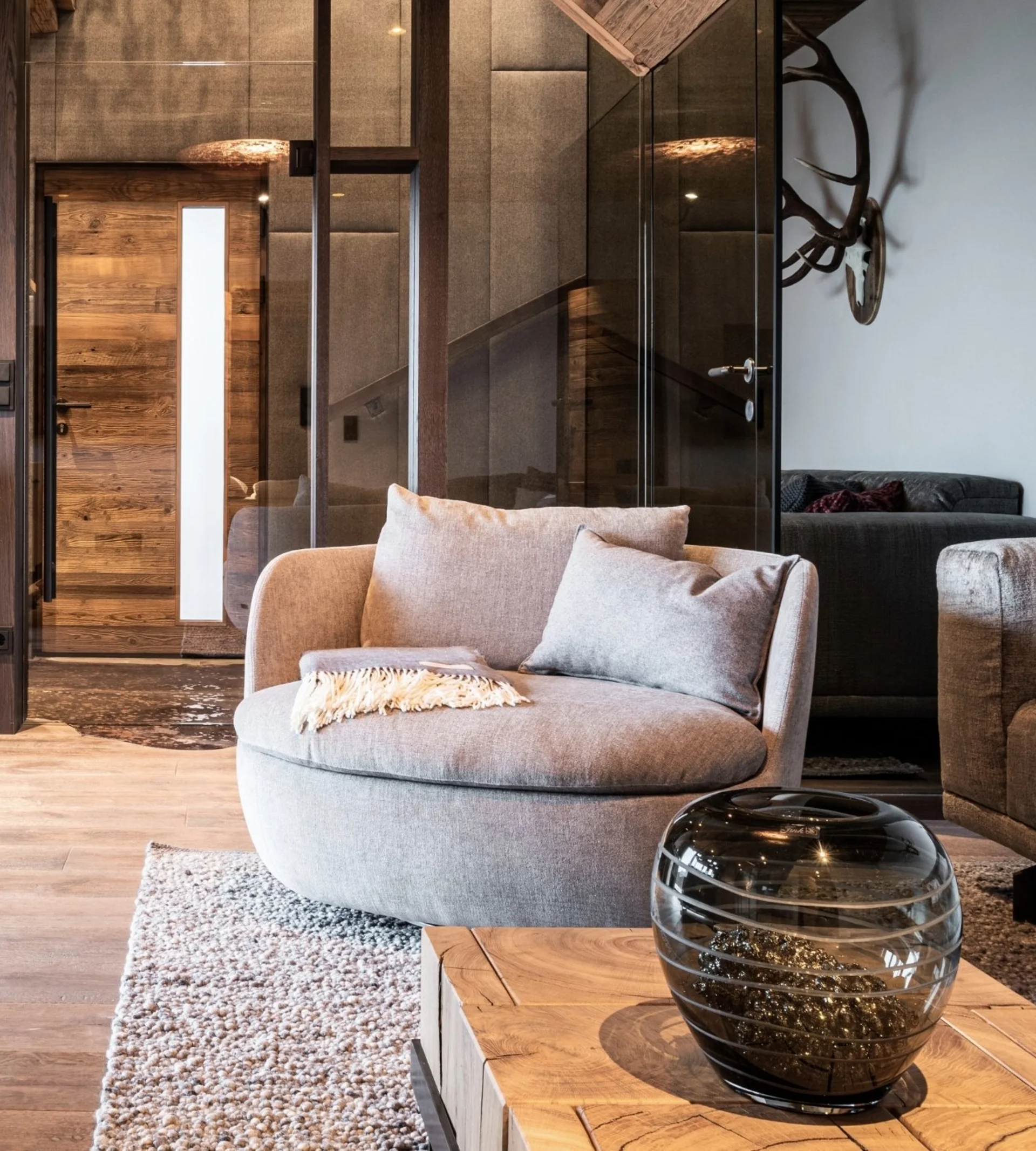 Babymoon im Gassner Baumhaus Moderner Wohnbereich mit grauem Sessel, Glasvase und Holzboden