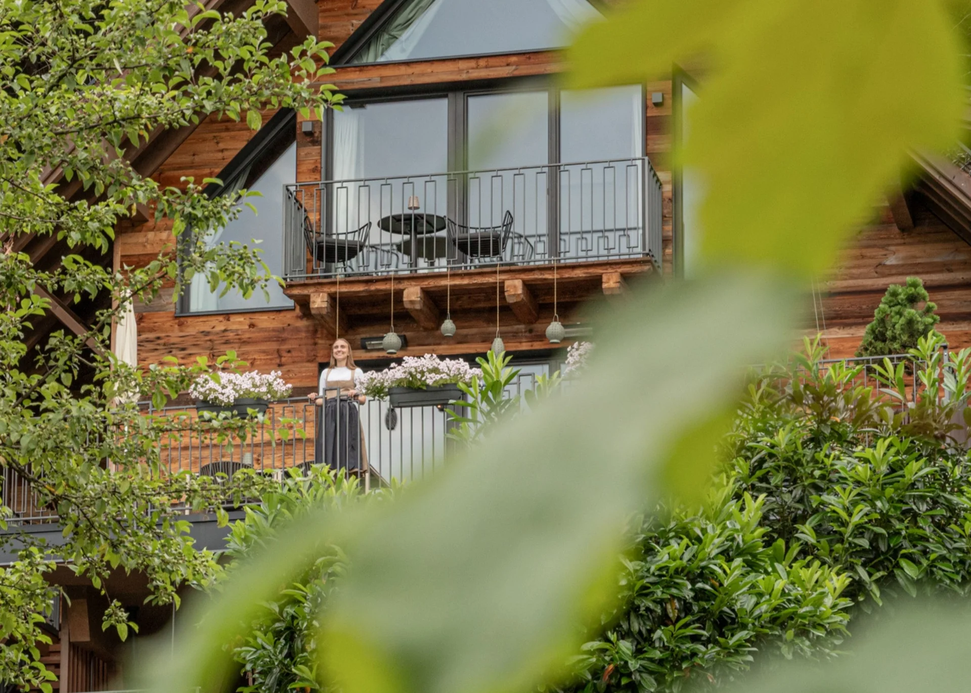 Babymoon im Gassner Baumhaus Holzhaus mit Balkon und einer Person, umgeben von grünem Laub