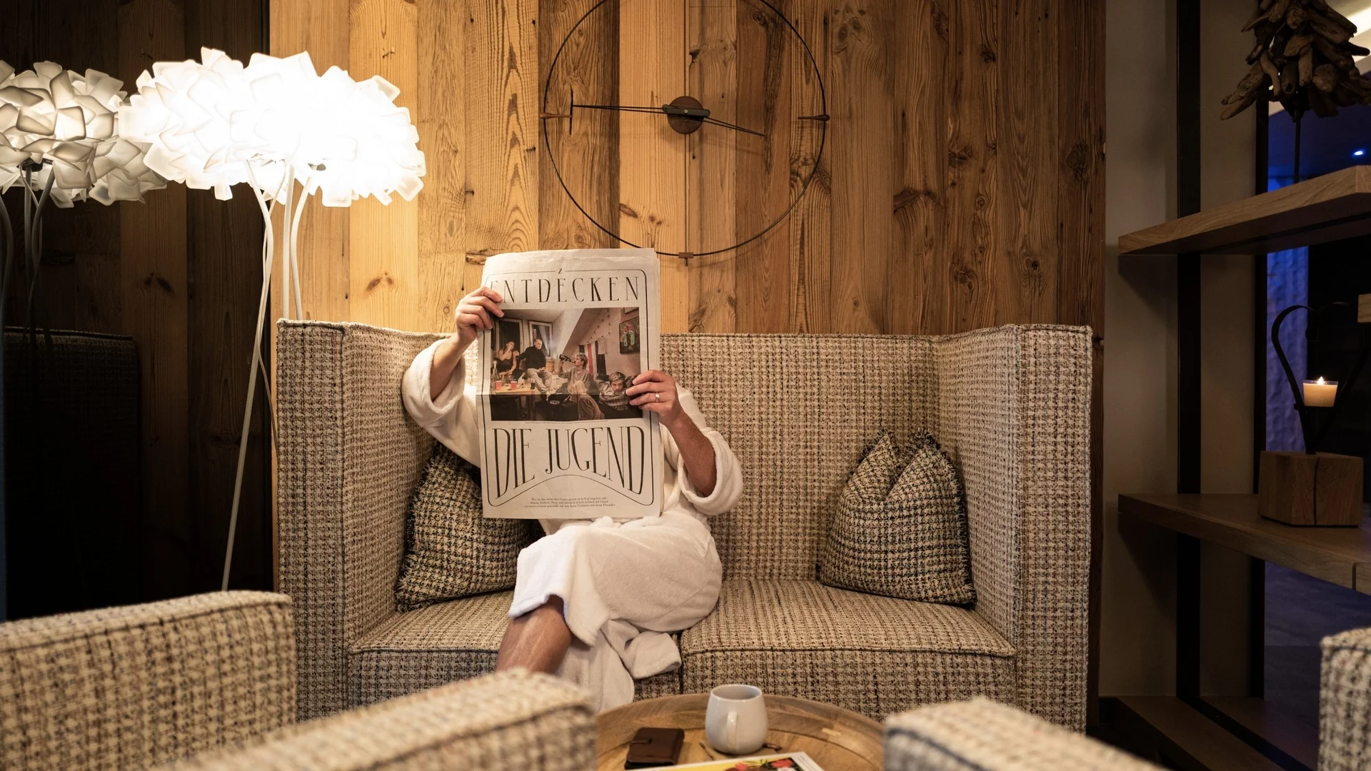 Auszeit für mich Person liest Zeitung auf gemütlicher Couch in warm beleuchtetem Raum