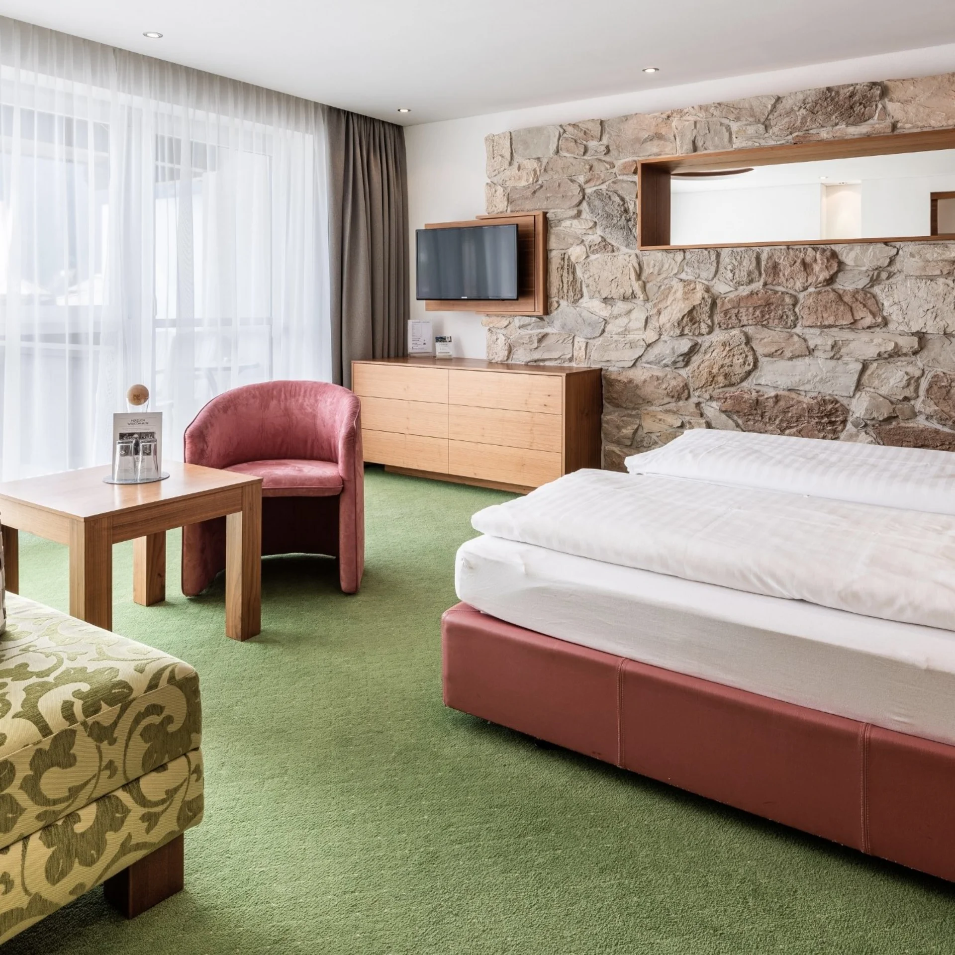Cozy hotel room with double bed, stone wall, and seating area