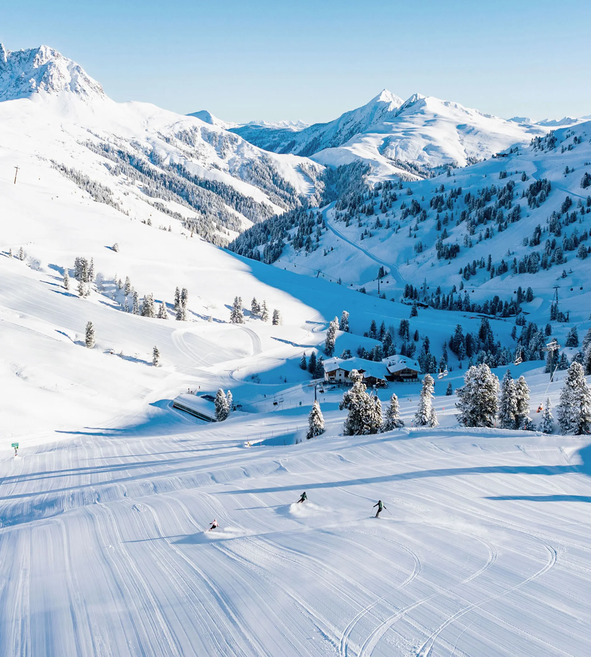 Skifahrer auf verschneiter Piste in den Alpen bei klarem Himmel