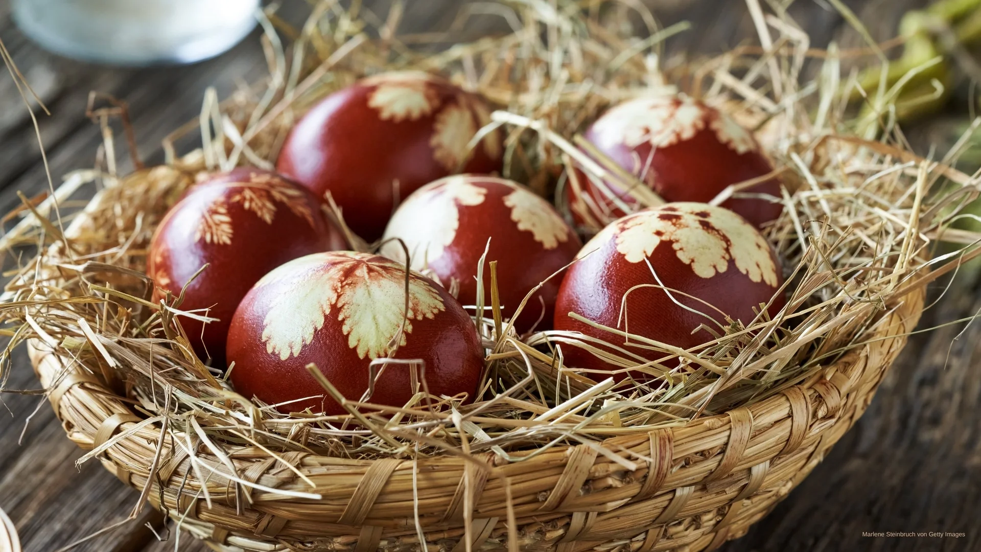 Ostereier mit Blattmustern in einem Korb mit Stroh