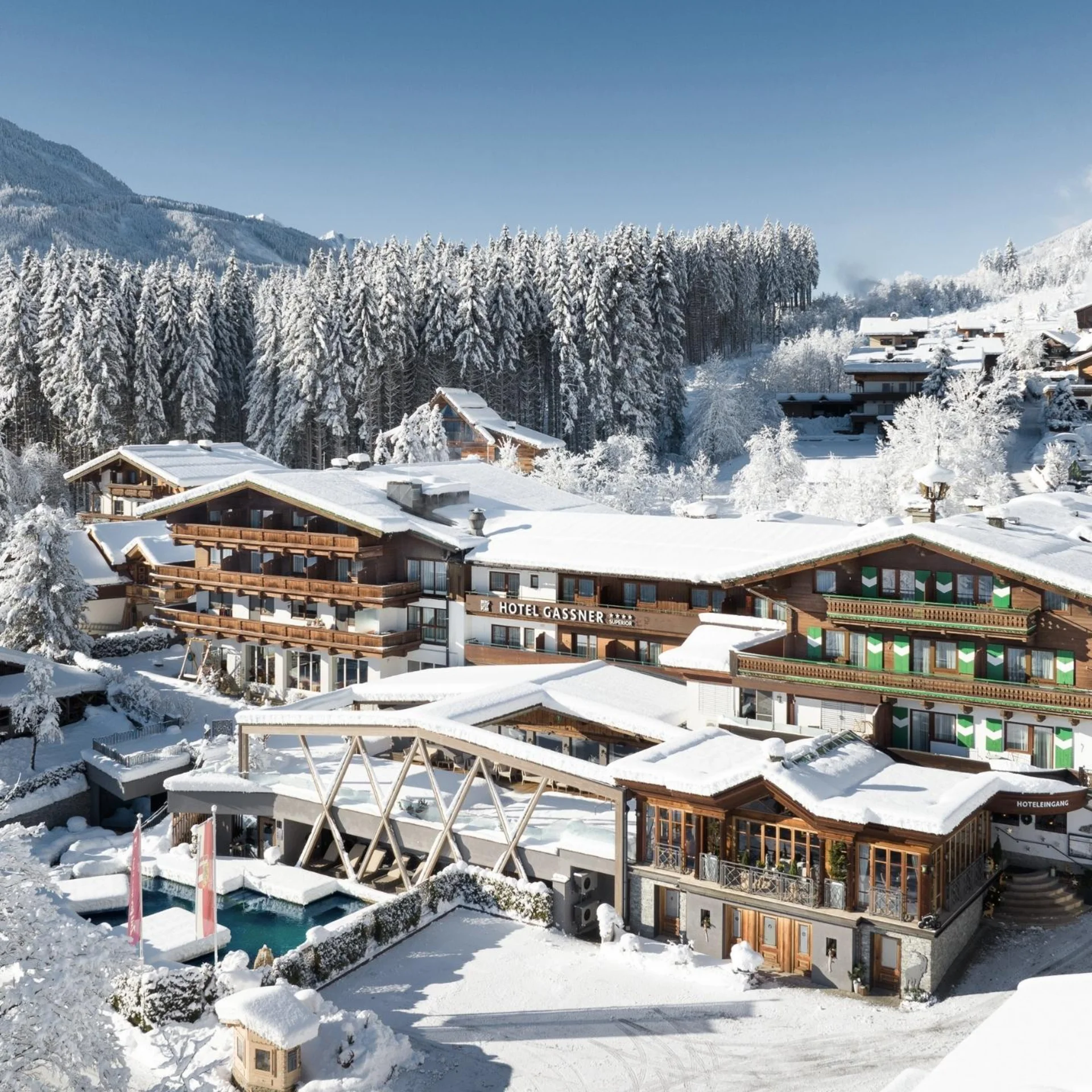 Snow-covered hotel and village in the mountains with trees and clear sky
