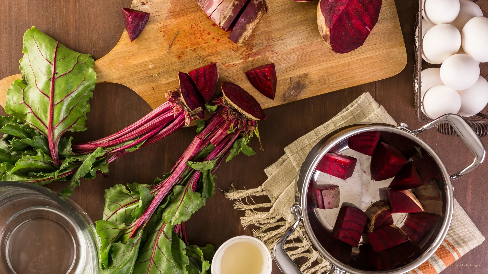 Geschnittene Rote Bete auf Holzbrett mit frischen Blättern und Eiern