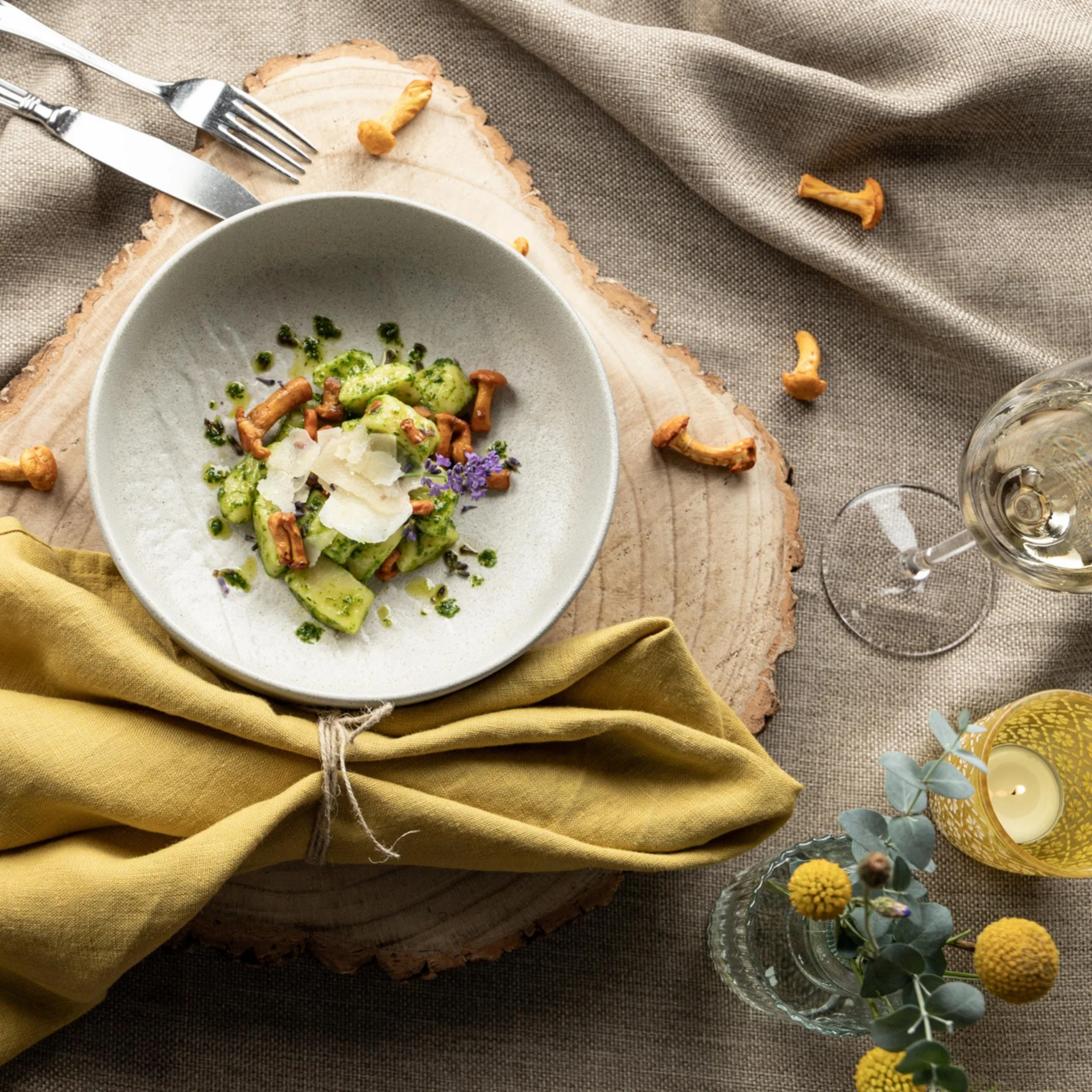 Schüssel mit Gnocchi, Pfifferlingen, Parmesan und grünem Pesto auf Holztisch
