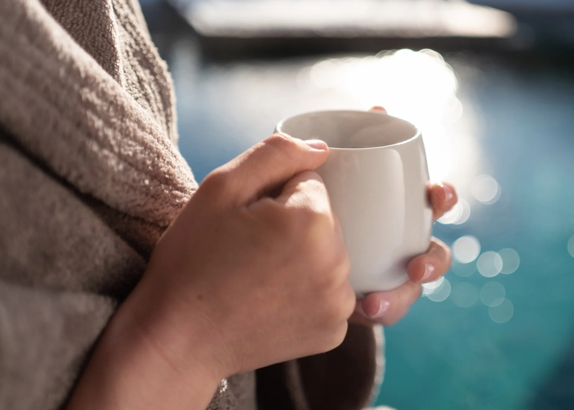 Day Spa Person hält weiße Tasse am Pool an einem sonnigen Tag