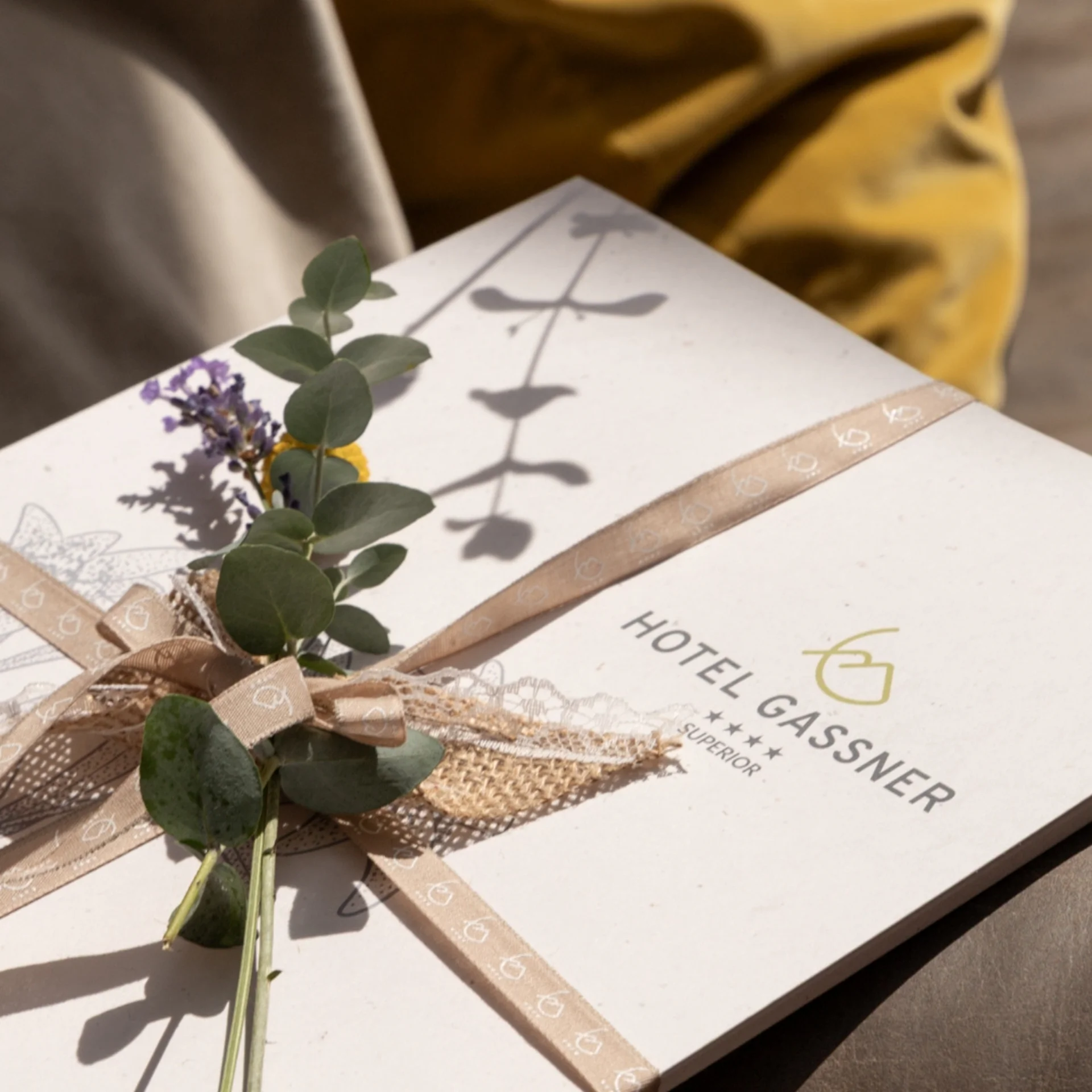 Wellness Gift box with ribbon and greenery on a chair at Hotel Gassner