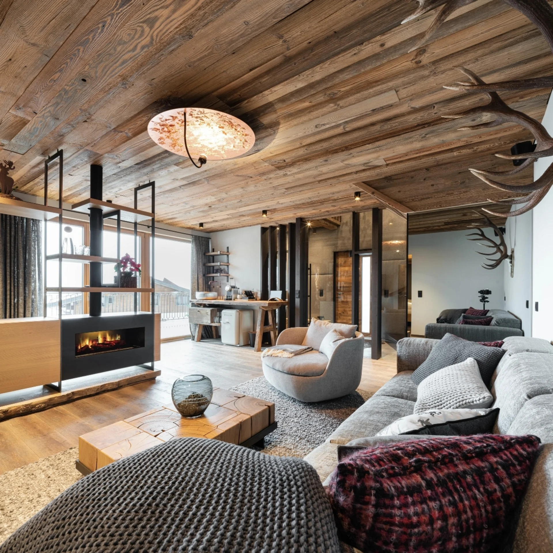 Gemütliches Wohnzimmer mit Kamin, Holzdecke und modernen Möbeln in Berghütte