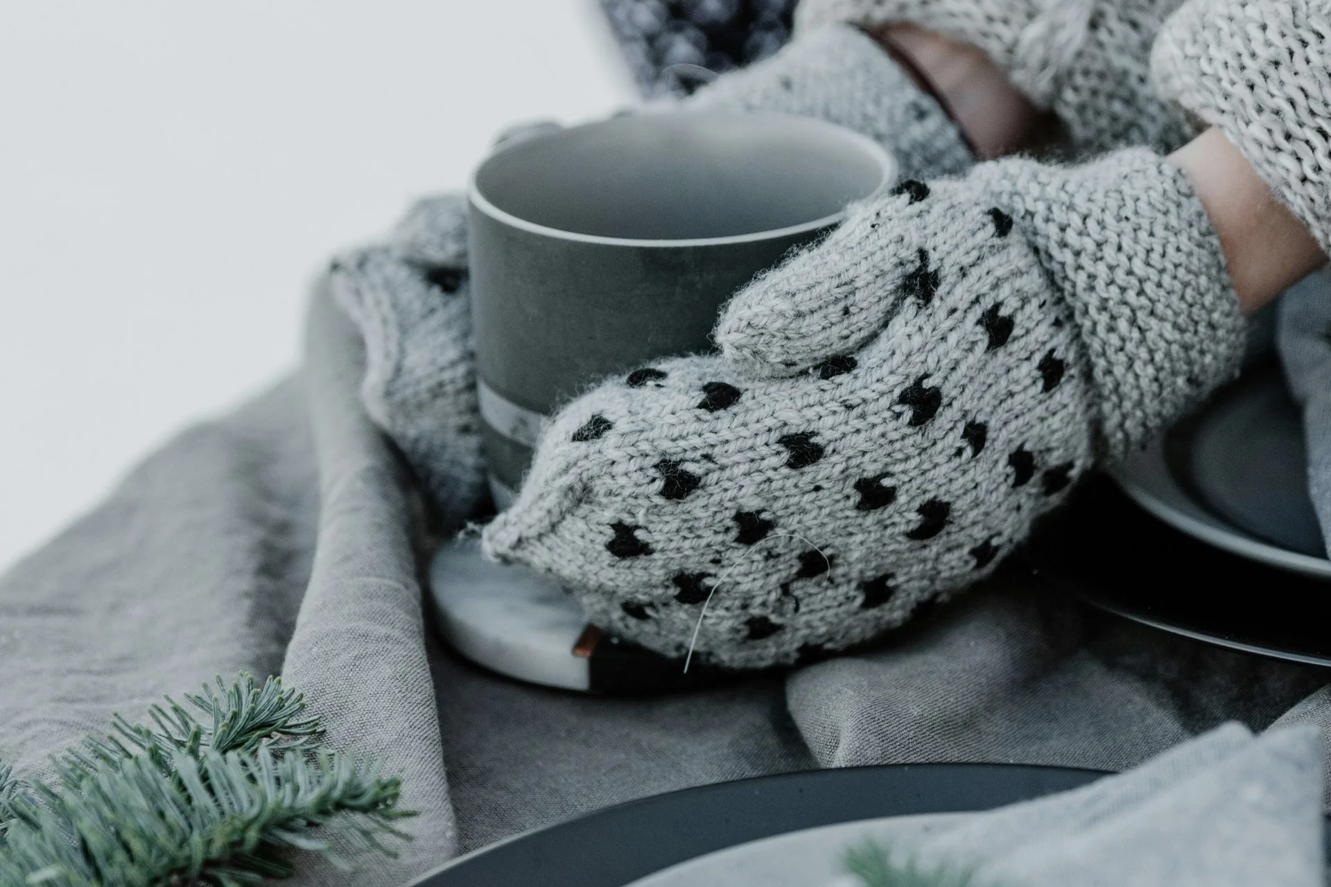 Eierlikör-Gugelhupf Person trägt graue, gepunktete Fäustlinge und hält eine Tasse bei winterlicher Dekoration