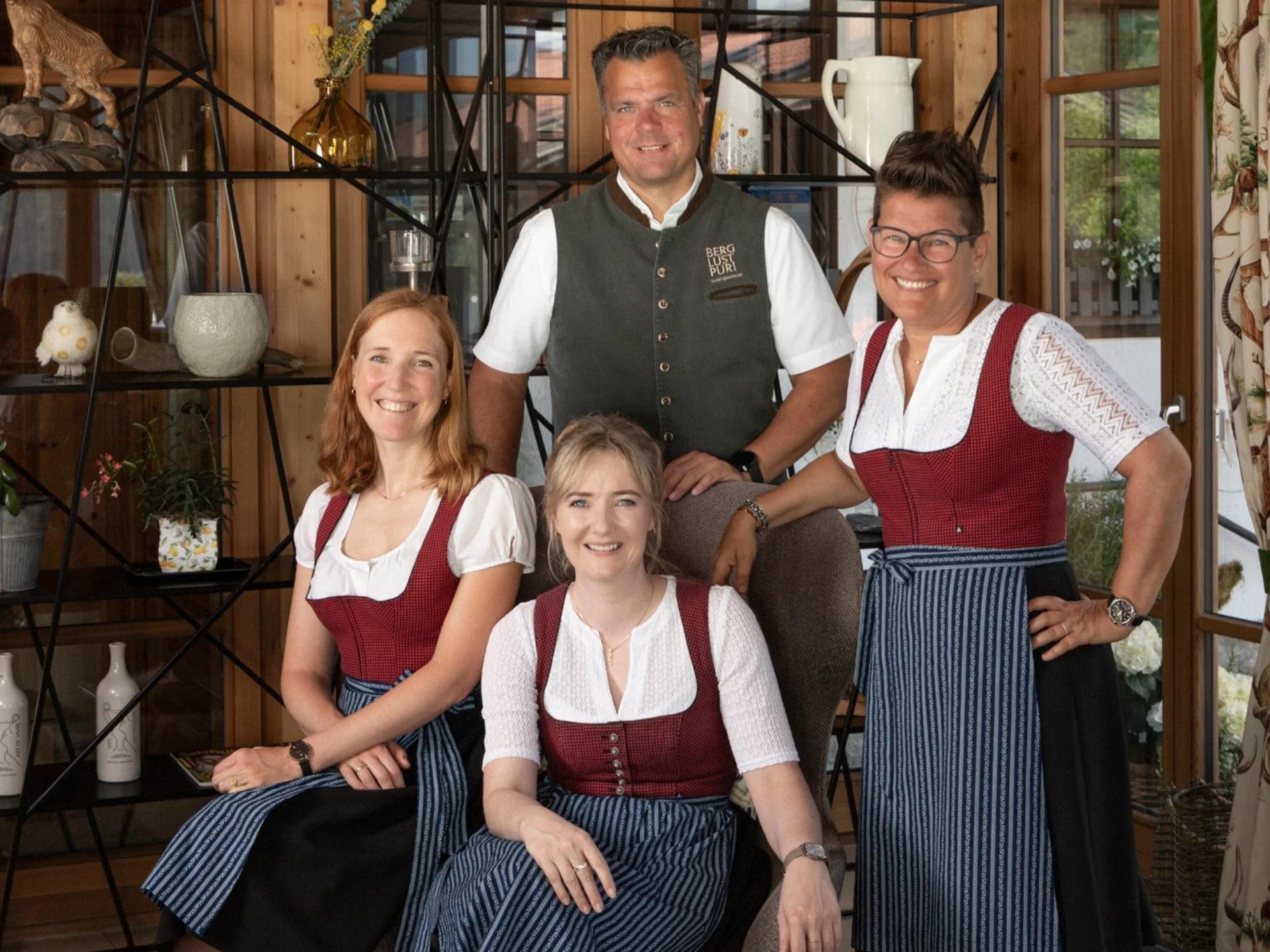 Four people in traditional attire in a wooden interior room