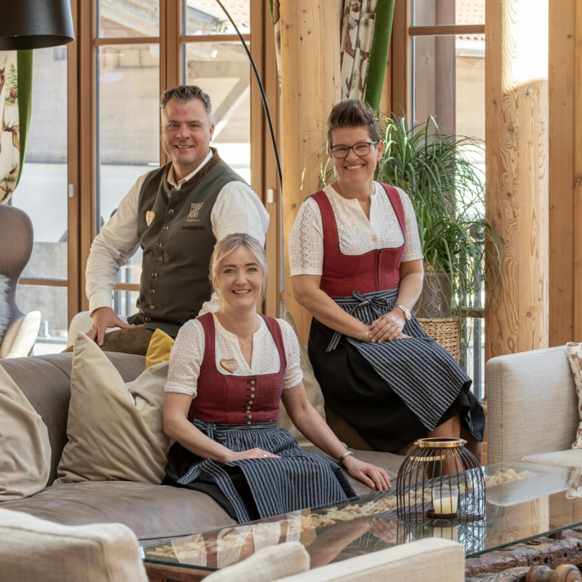 Vier Personen in traditioneller Tracht in einem Holzzaum eingerichteten Raum