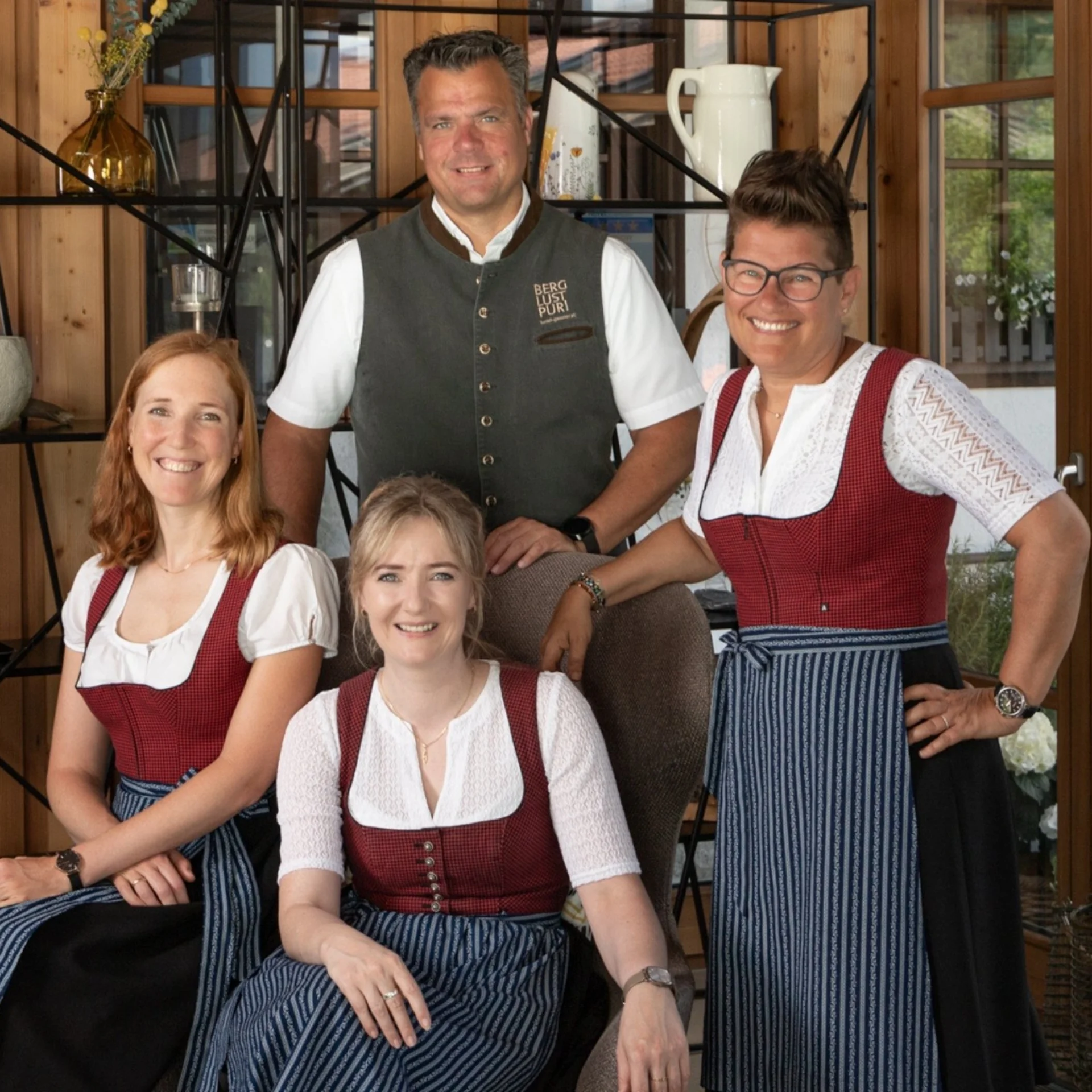 Baumhaus Vier Personen in traditioneller Tracht in einem Holzzaum eingerichteten Raum