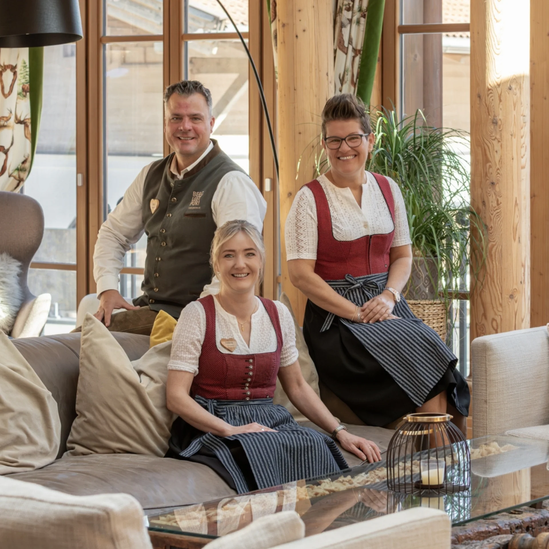 Vier Personen in traditioneller Tracht in einem Holzzaum eingerichteten Raum