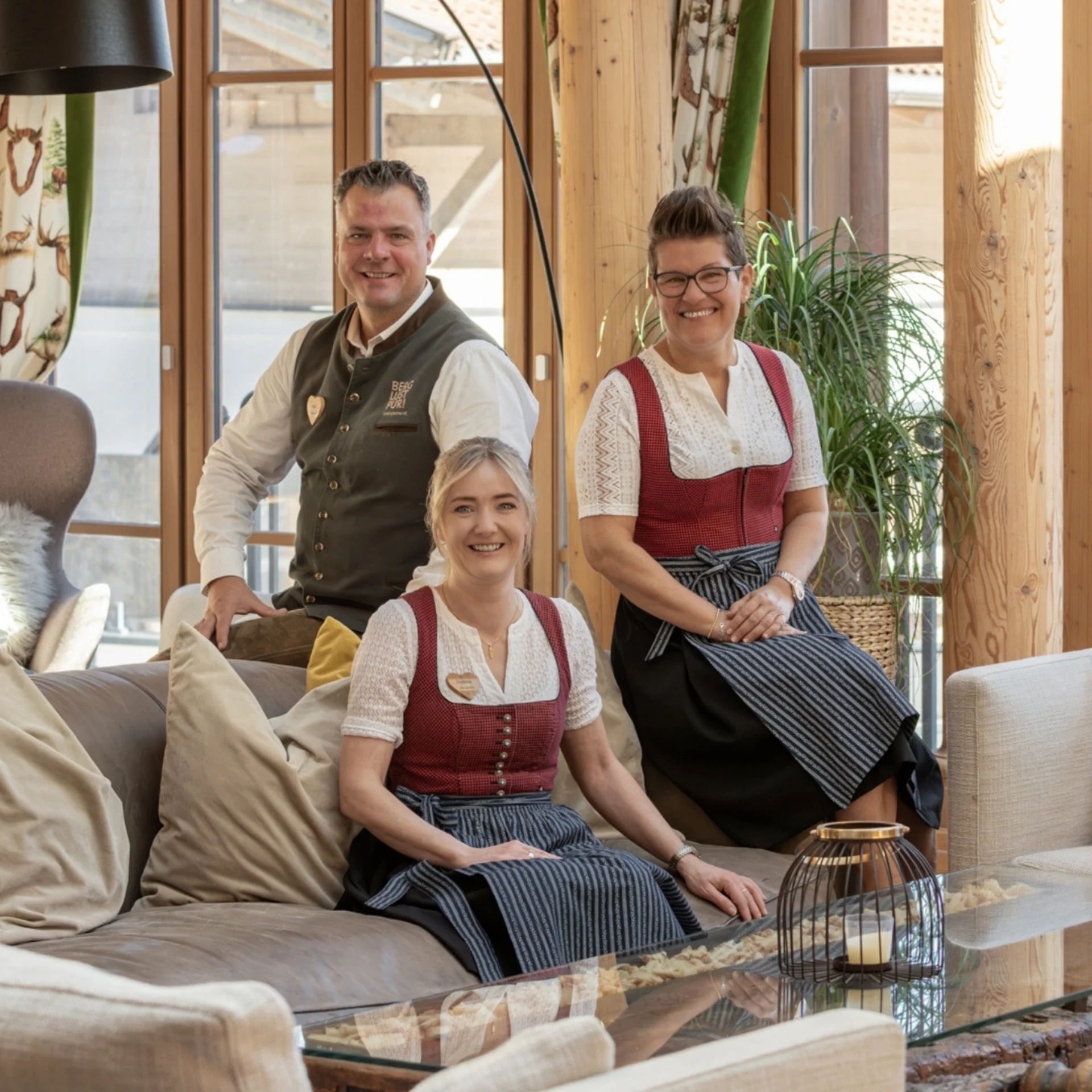 Ei.Feel.Good Vier Personen in traditioneller Tracht in einem Holzzaum eingerichteten Raum