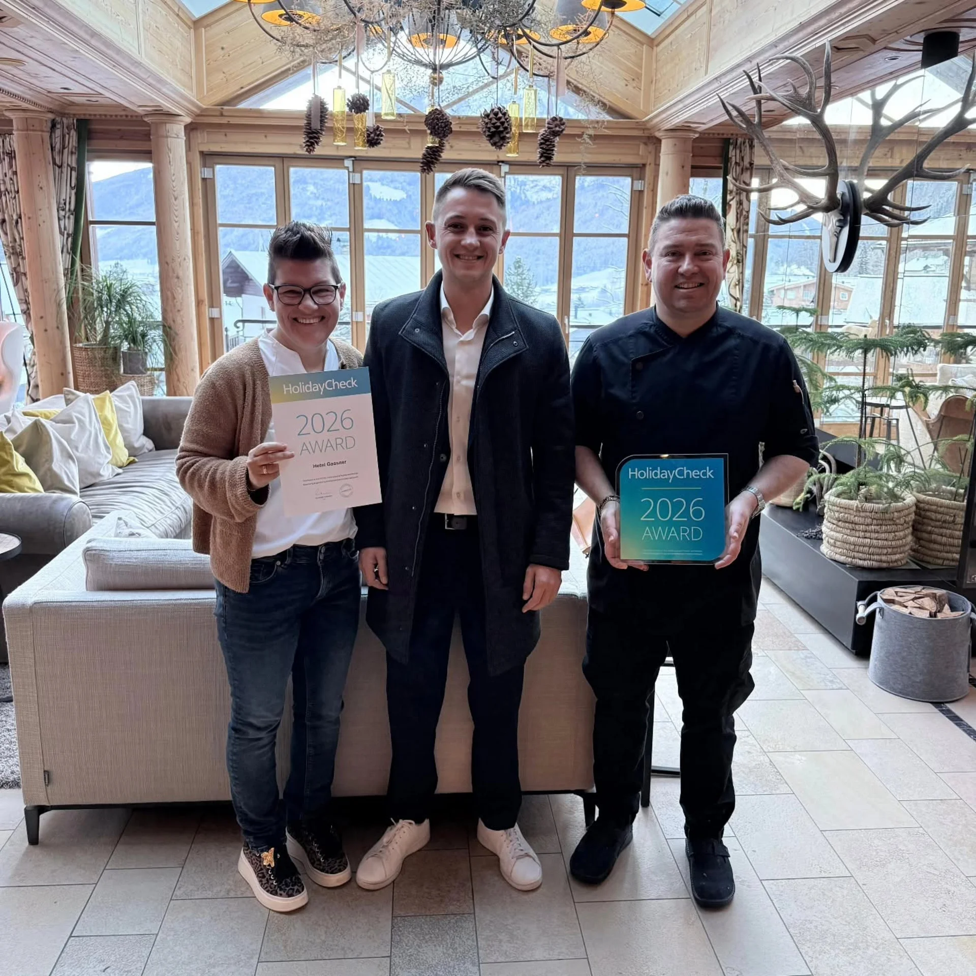 Bewertungen Drei Personen präsentieren HolidayCheck 2026 Awards in einer hellen Hotellobby