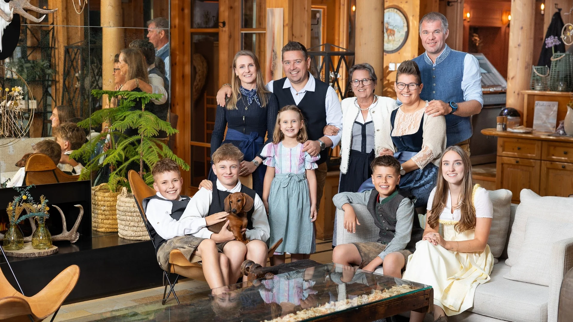 Your hosts Large family with children in traditional outfits outdoors by hedge and mountains