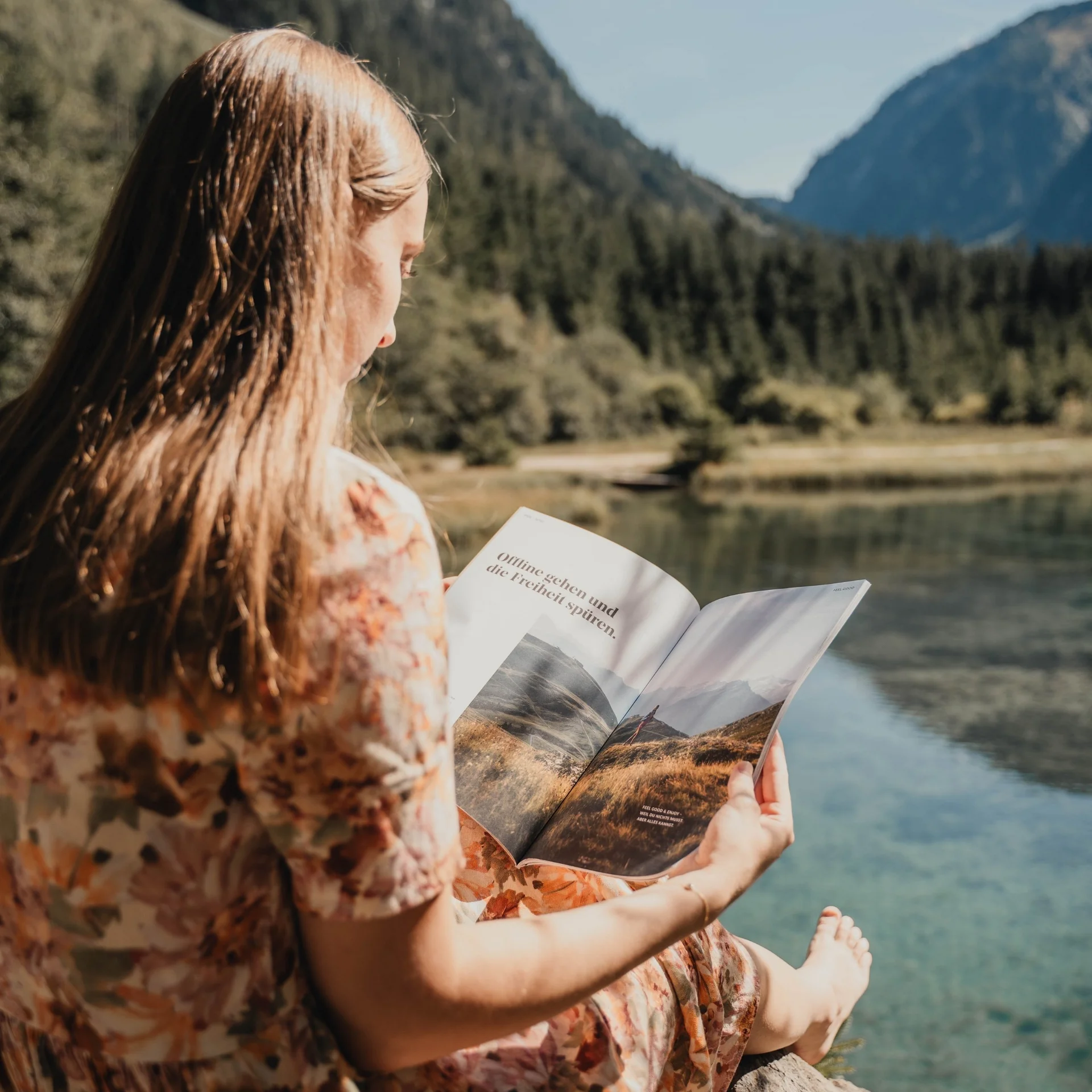 Wandern Frau liest Magazin am See mit Berglandschaft im Hintergrund