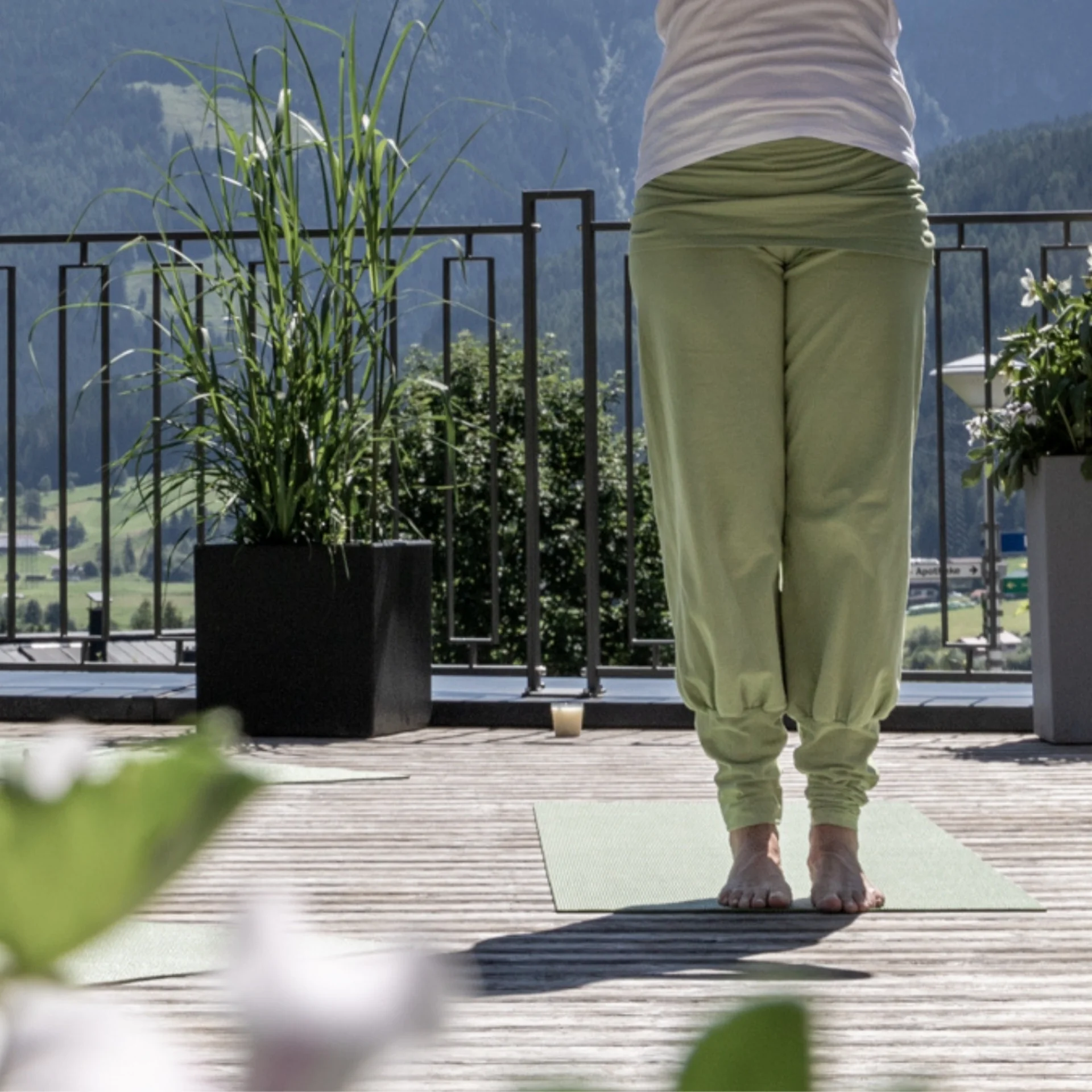 Person standing on tiptoes on terrace with plants and mountain view