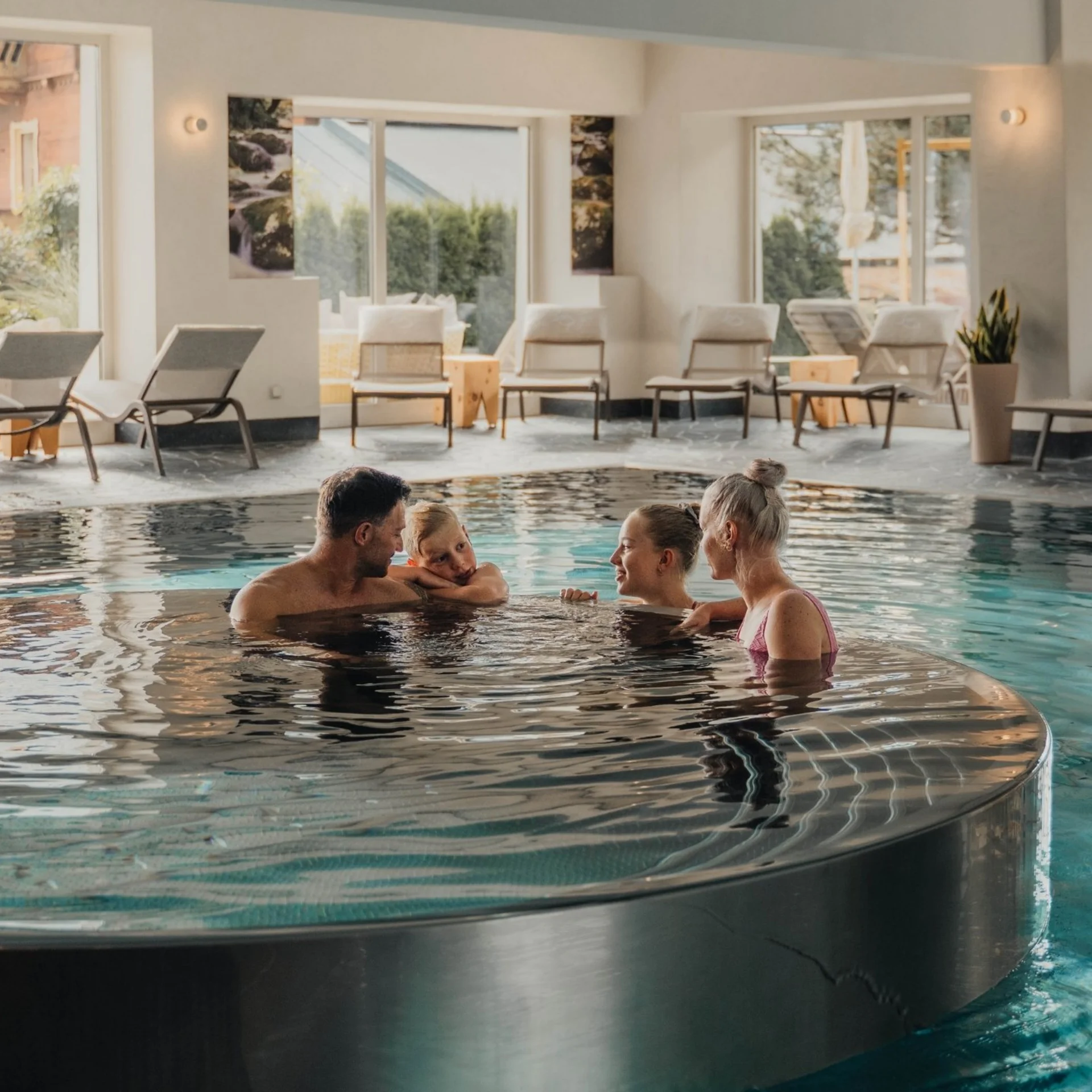 Family relaxing in round whirlpool inside indoor pool area