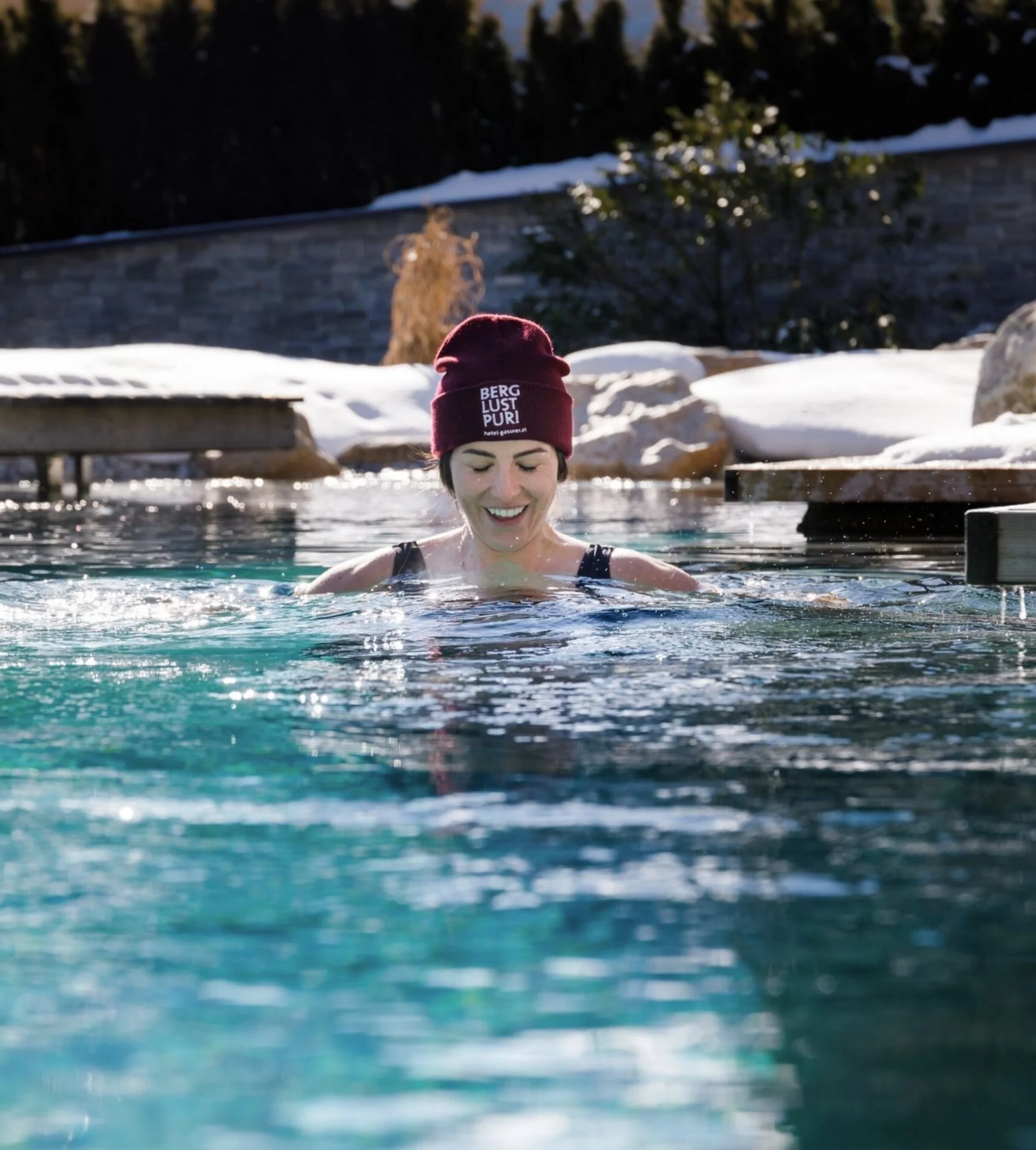 Massagen Frau im Winter draußen im Pool mit Mütze und Schnee im Hintergrund