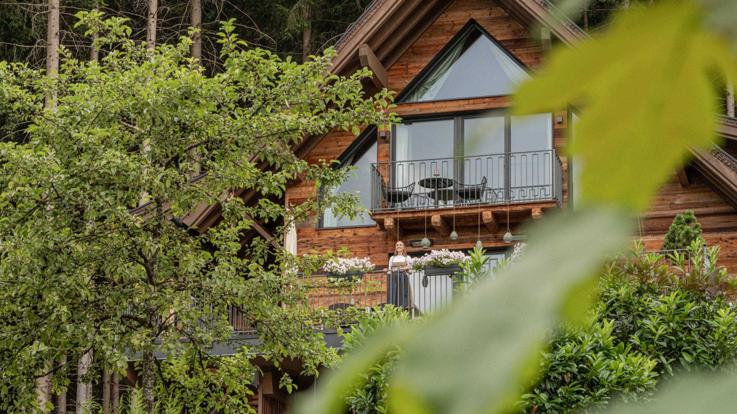 Untersulzbachtal Wooden chalet with balcony and woman, surrounded by trees and plants